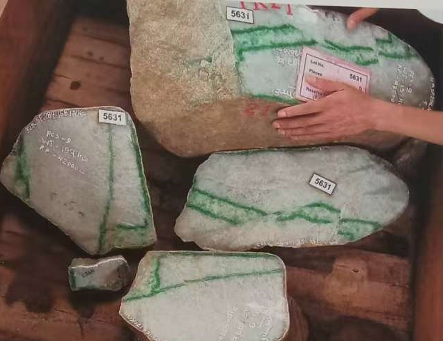 图4 玉料中的色带被挤压措断后,产生了数条原生裂堑,其中大部分被矿物质充填结晶,形成水线。
